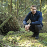 Justin Hartley crouching down on a mossy forest floor in a scene from 'Tracker' (2024)