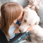 Young girl in wheelchair hugs a service dog.