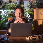 Actor Walton Goggins posed in front of a workspace and a laptop.