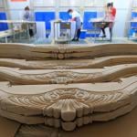 Carved wooden parts of a furniture set lined for production.