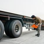 A mechanic inspecting a cargo truck for transport.
