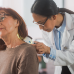 Dermatologist using a medical magnifying glass to inspect the skin of an elderly woman patient