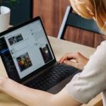 A woman browsing on a laptop looking at the feed of a user on a social media app.