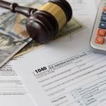 Tax law changes concept showing tax forms, bank notes, a calculator and a judge gavel.
