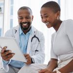 Female employee availing healthcare benefits happily consulting with a doctor.