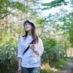 A young woman enjoying the view of the sky during summer in a forest.