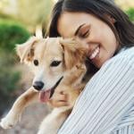 Woman smiling while holding her pet dog.