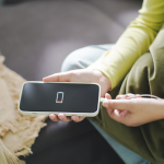 Person's hands plugging a low battery phone into a charger
