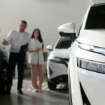 A car agent helps a woman look for a car to purchase.