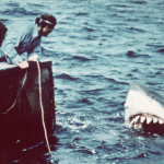 Actors Richard Dreyfuss (left) (as marine biologist Hooper) and British author and actor Robert Shaw (as shark fisherman Quint) look off the stern of a fishing boat at the terrifying approach of a giant shark in a scene from the film 'Jaws' directed by Steven Spielberg, 1975.