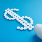 White pills spilling from a bottle forming a dollar symbol.