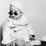 Vintage studio portrait of a baby wearing a beret and sunglasses