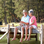 Senior couple sitting on a lakeside dock and fishing
