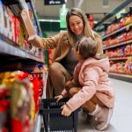 A woman and little girl shopping for snacks in a grocery aisle. 