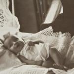 Baby girl laying in bed, circa 1920s.