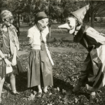 Three girls amuse each other with their masked costumes as they prepare for Halloween festivities in the College Hill neighborhood of Cincinnati, Ohio, 1929.