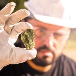 Miner holding gold nugget, with point focus on the nugget