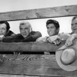 Dan Blocker holds his hat while standing with others in a scene from the TV series “Bonanza” (1959–1973).