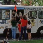 View of a small group of children and teenagers at a Bungalow Bar-brand ice cream truck on Fitchett Street (near 64th Road), in the Rego Park neighborhood, Queens, New York, New York, July 1981. 
