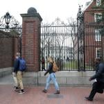 People walk through Harvard University's campus with a box in Cambridge, MA