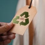 Close up of hand holding a tag that says Made By 100% Recycling Materials attached to a product.
