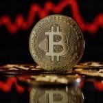 A physical representation of a bitcoin, with the B symbol prominently displayed in the center of the coin, in front of a background of a red, downward-trending line graph.