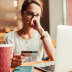 A woman holds a credit card and looks at her laptop with concern.