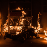 A fireman on the floor in a burning room.