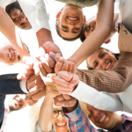 People smiling with their hands touching in the middle of a circle.