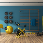 A home gym with fitness equipment, including weights on the wall, a weight bench, an exercise ball, a stationary bike, and punching bag.