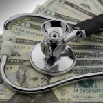 A stethoscope sitting on top of a pile of $20 bills. 