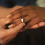 Two hands together with an engagement ring.