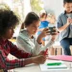 Kids looking at phones in a classroom.