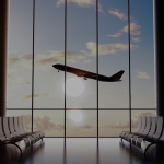 An airport terminal building with rows of empty chairs and airplane seen through the windows.