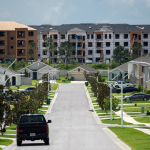 A neighborhood of nice homes with apartment buildings under construction in the background.