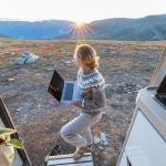 A woman working remotely near a mountain sunset.