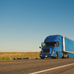 A large blue truck on a rural road. 