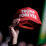 A supporter holds a Trump Forever hat in the air.