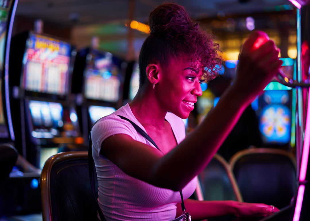A person smiling while gambling using a slot machine.