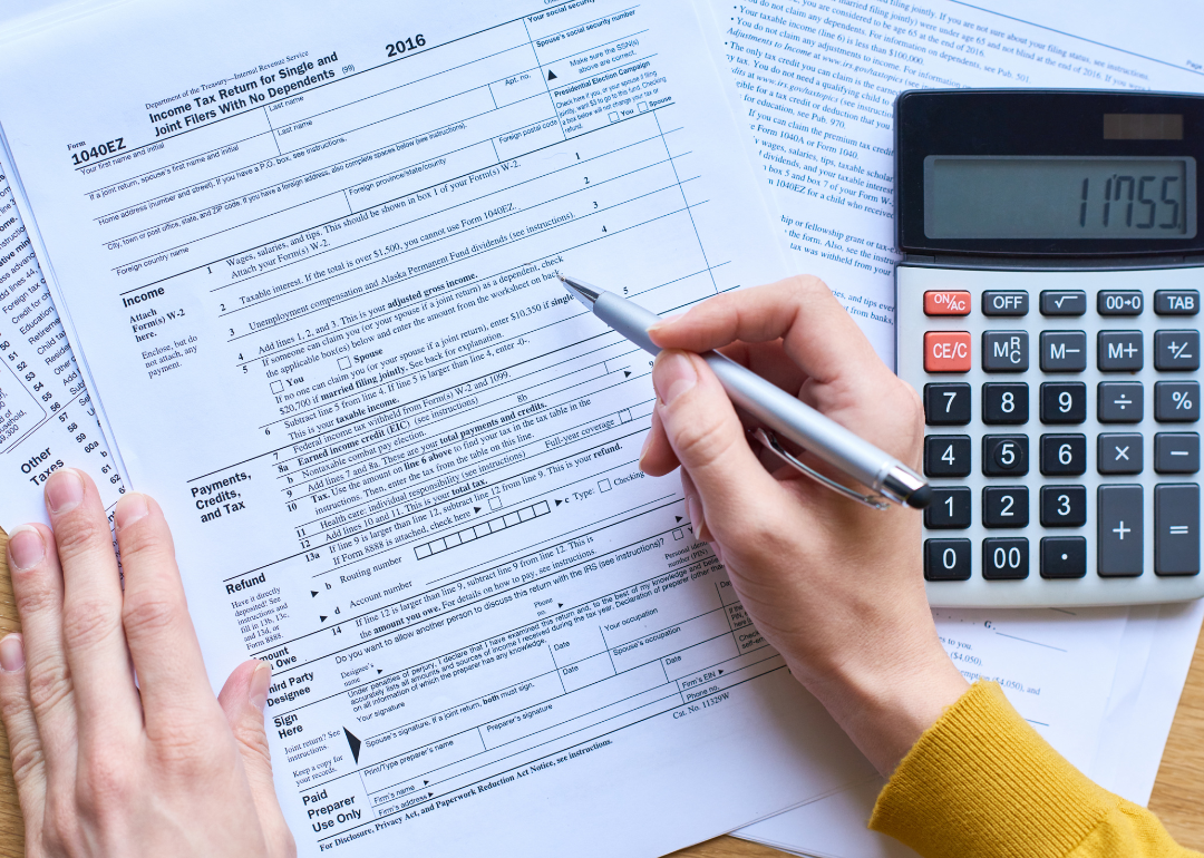 A person using a calculator to complete a tax form.