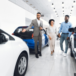 A salesman showing luxury cars to a couple at a car dealership
