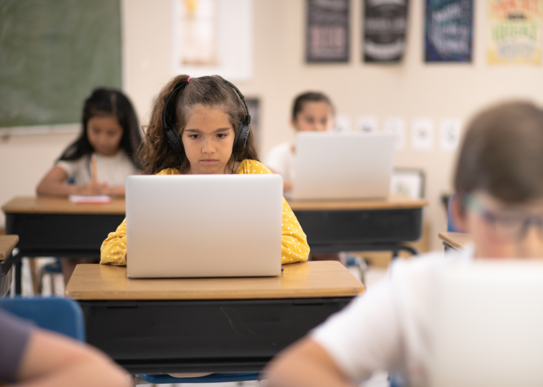 Students working on laptops in an elementary school classroom.