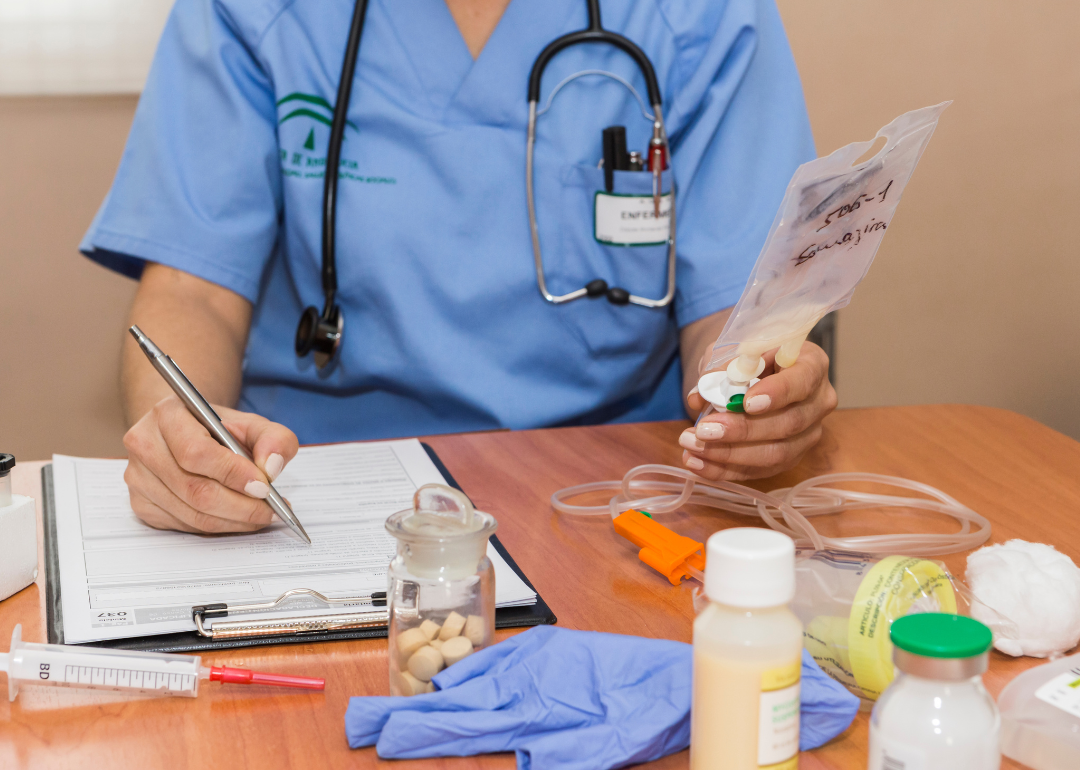 A physician writing down medical information in their office.