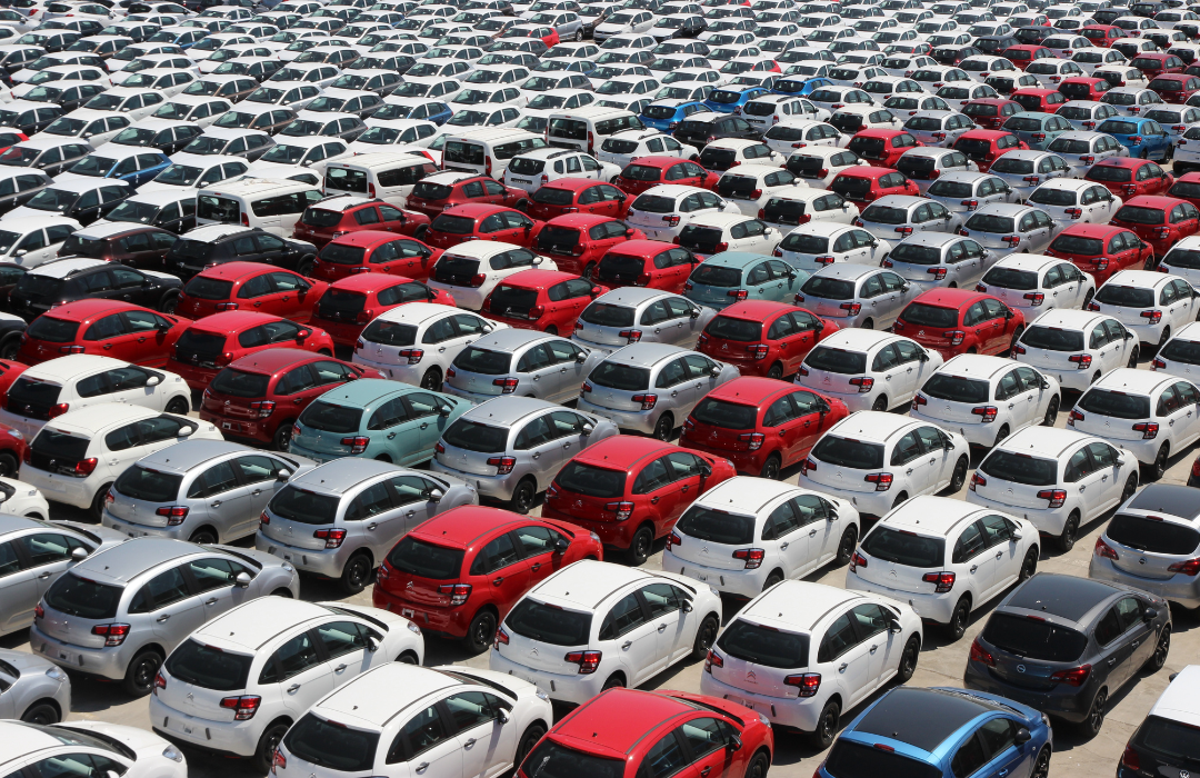 A crowded parking lot full of red and white cars.