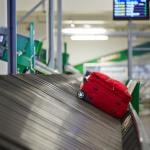 A red suitcase on a baggage belt.