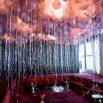 Many pink balloons hanging from a ceiling for a party.