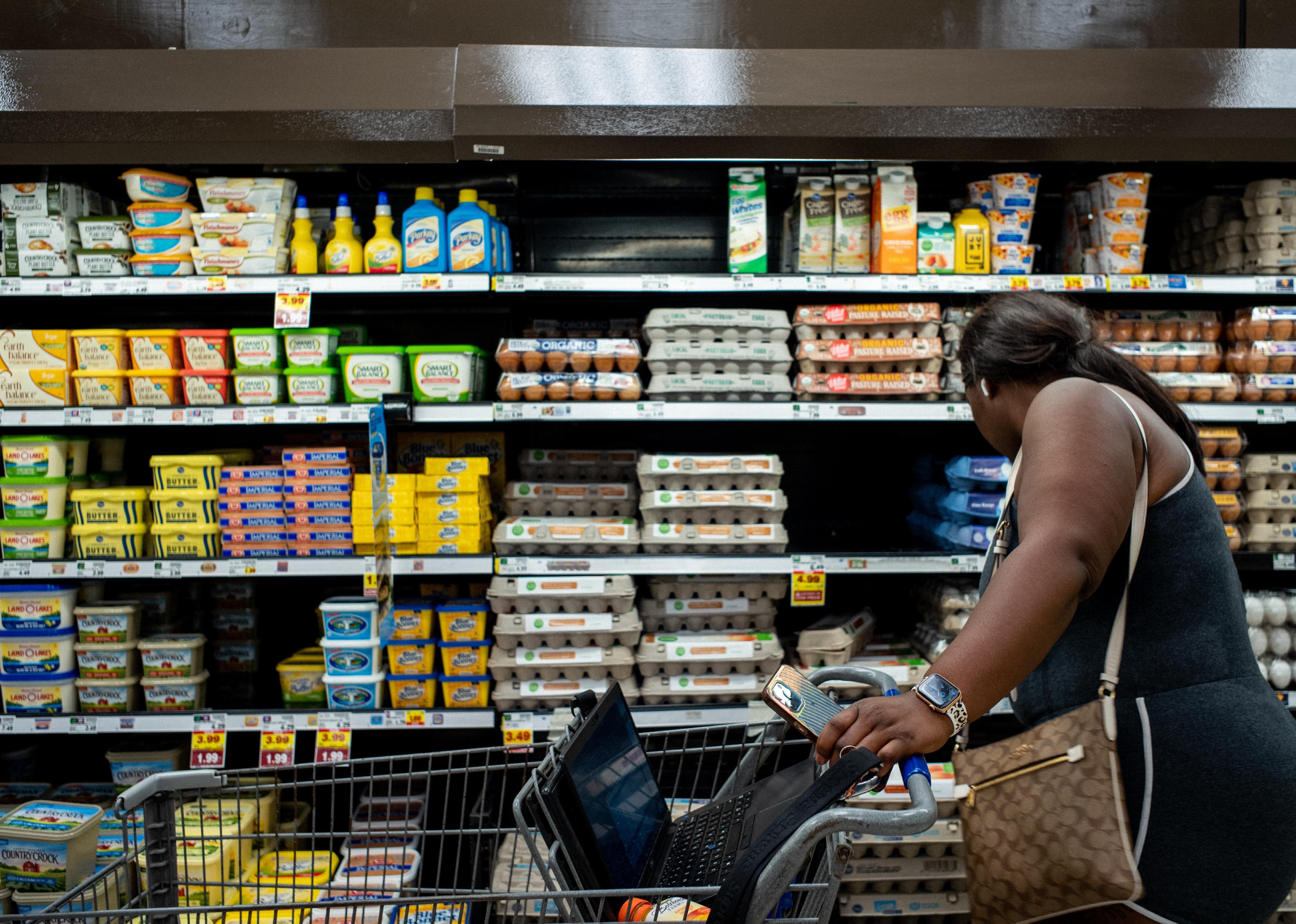 A woman shops for eggs in a grocery store.