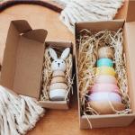 Wooden baby toys in boxes in front of a rainbow toy made of rope.