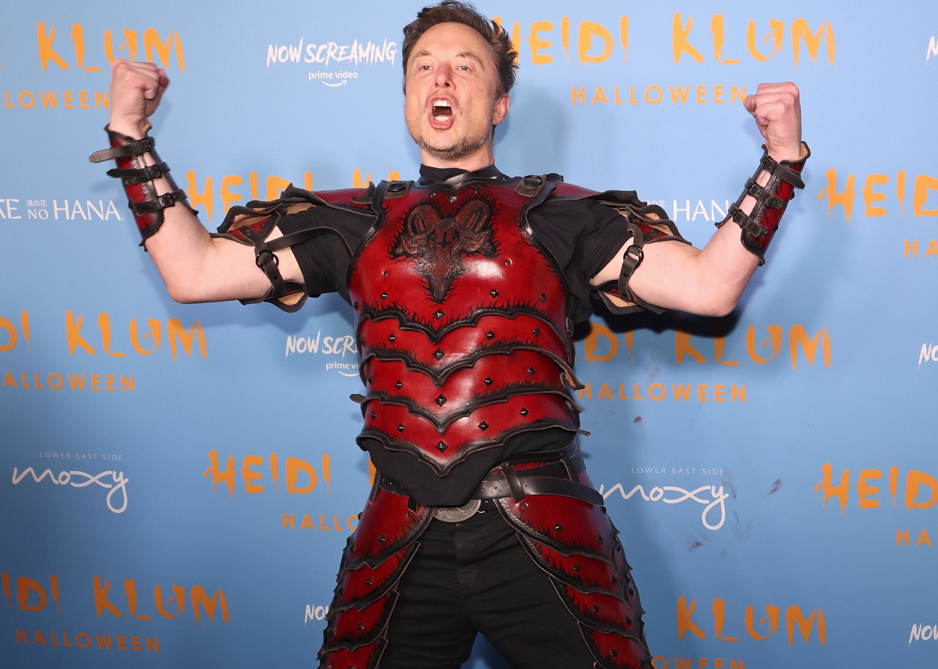 Elon Musk wearing armour as a Halloween costume and fleing his muscles.