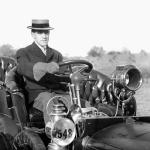 A wealthy 19th century man in his leather outfitted open-air automobile. 